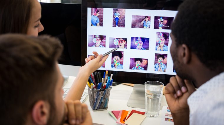 Graphic designers discussing over computer at their desk in the office
